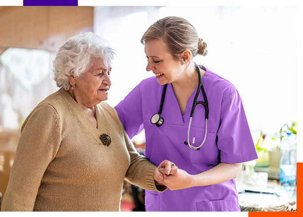 身着紫色手术服的妇女帮助一位老年妇女行走