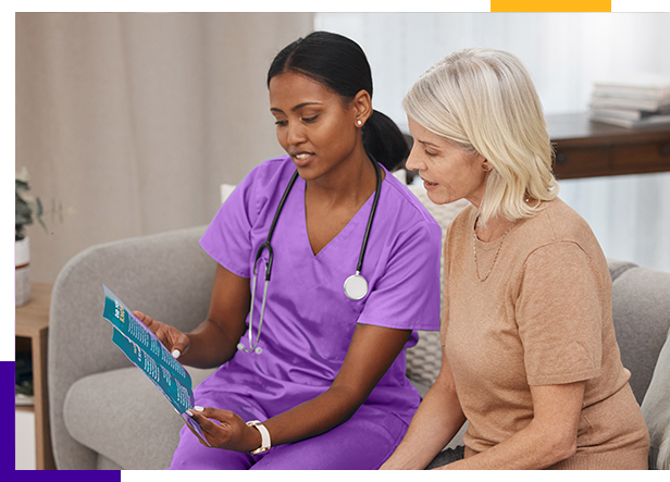 Woman in purple scrubs reading to a woman sitting next to her