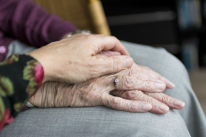 a comforting hand placed atop an older person’s hands – Amazing Home Care