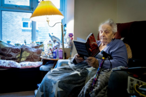 an elderly woman reads a book in a care facility – Amazing Home Care